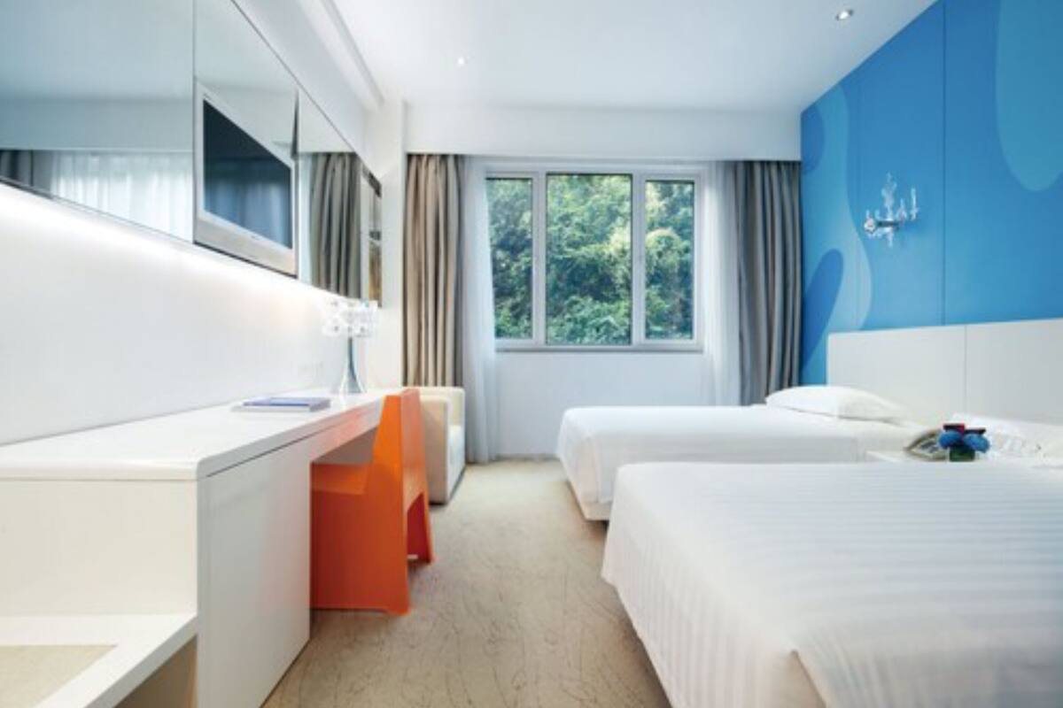 Una habitación de hotel con cama, escritorio, silla y ventana con cortinas.
