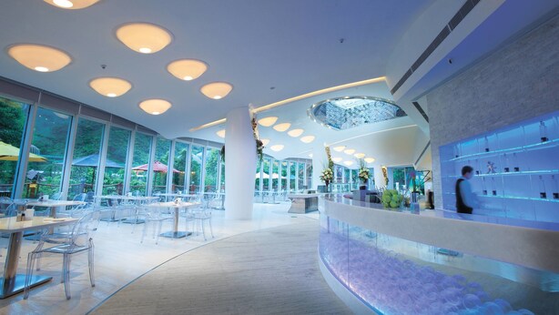 A spacious indoor area with large windows, a reception desk, and a seating area with tables and chairs.