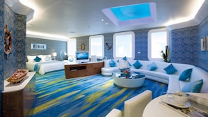 A modern hotel room with a large bed, a sofa, a coffee table, and a TV.