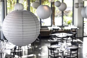 Ein Restaurantinnenraum mit runden Tischen und hängenden Papierlampen.