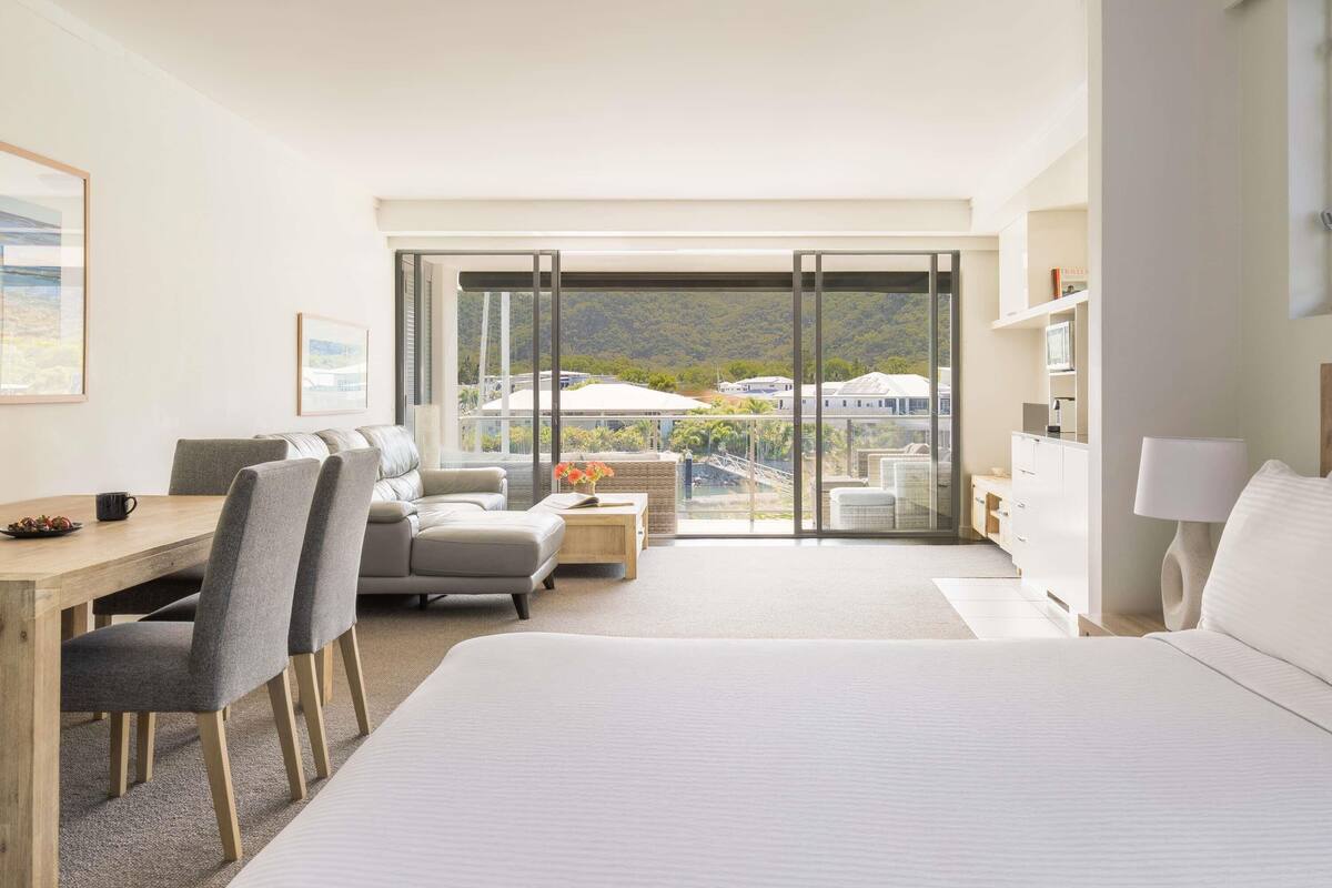 Une chambre d’hôtel comprenant un lit, un bureau, un canapé et un balcon avec vue sur un paysage vallonné.