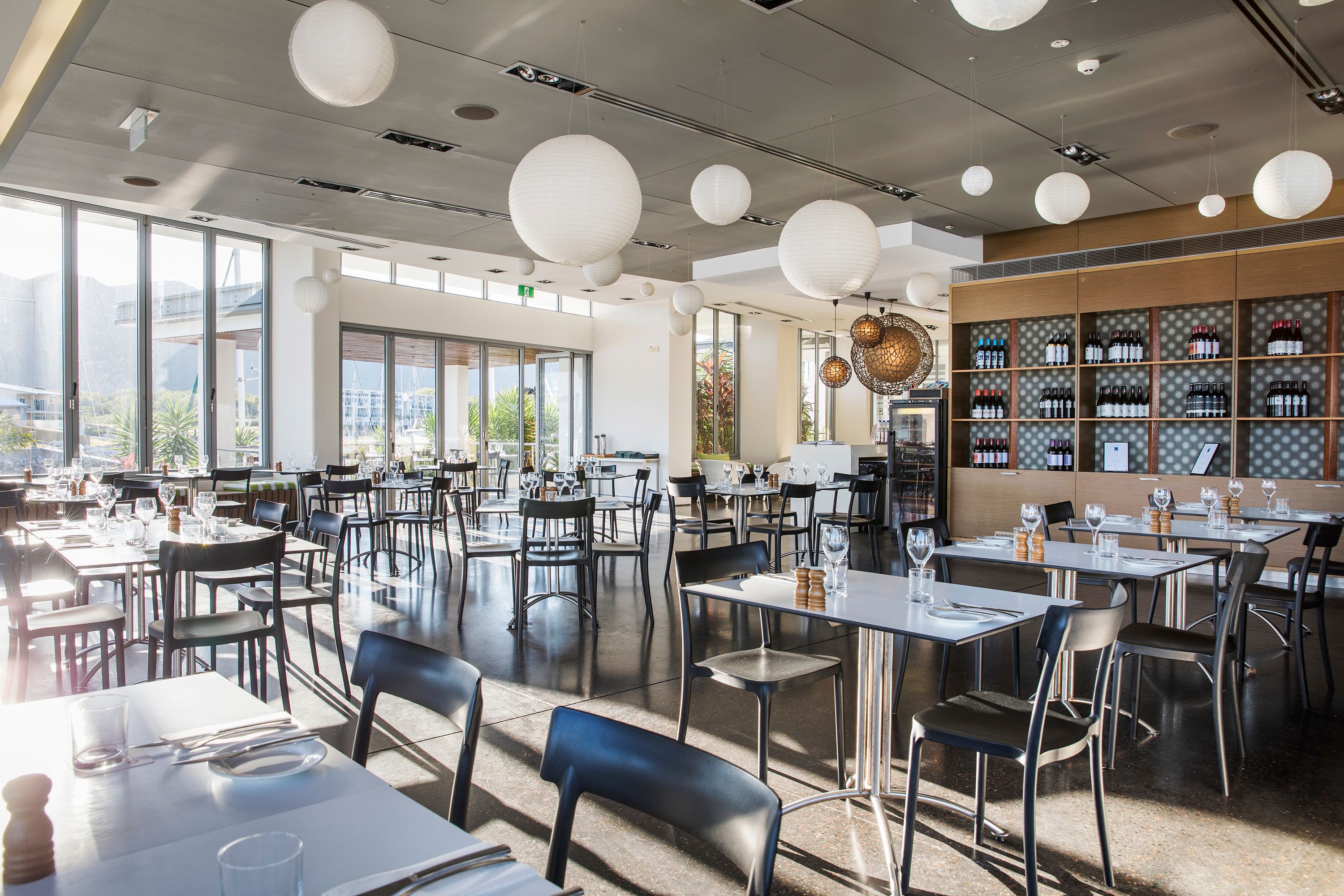 A spacious restaurant with high ceilings, large windows, and a variety of seating arrangements.