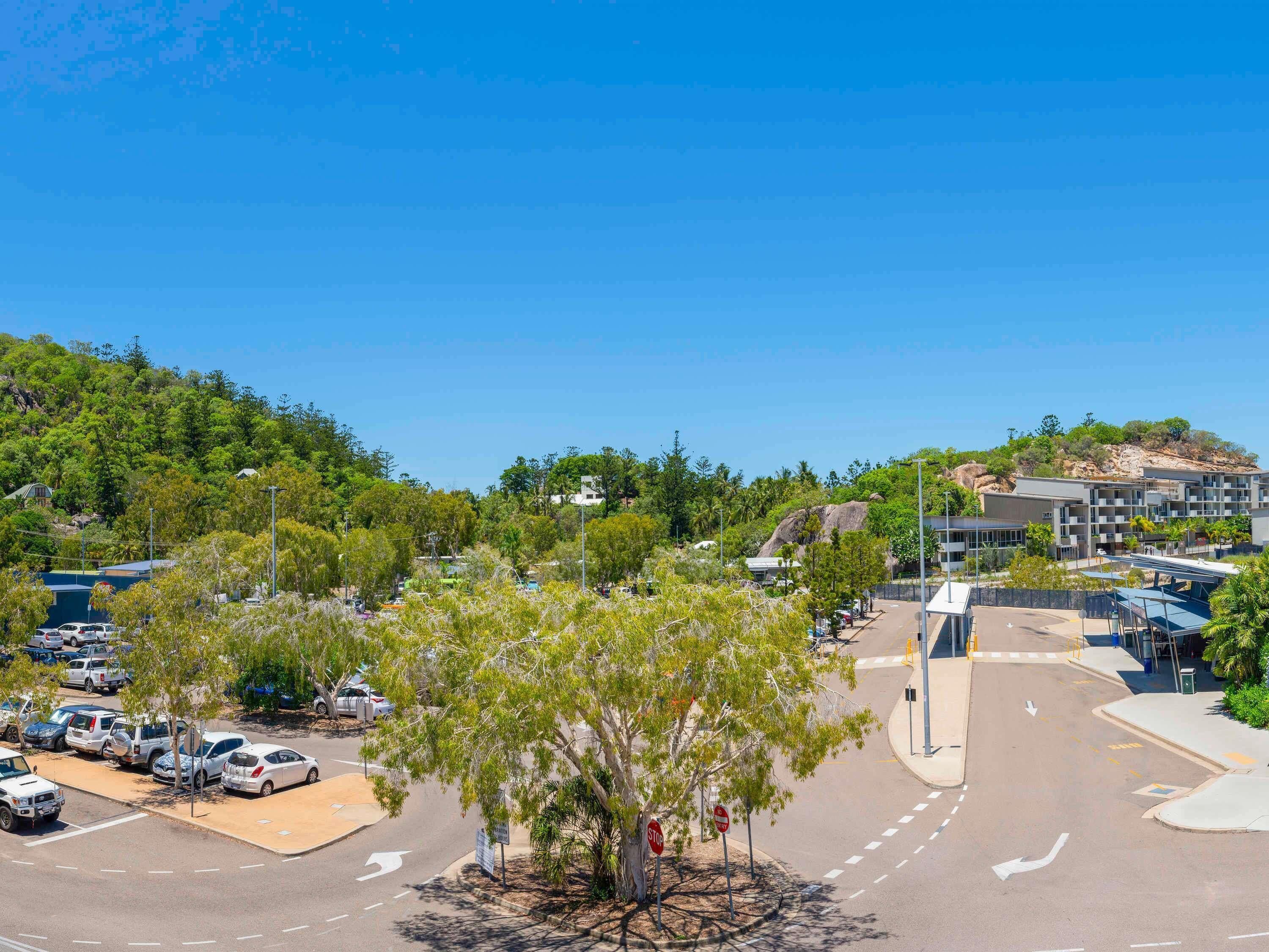 A parking lot with cars, a stop sign, and a building with multiple floors.