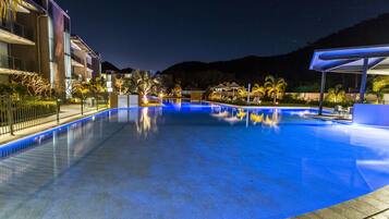 Relax by the pool surrounded by palm trees and modern buildings with balconies.