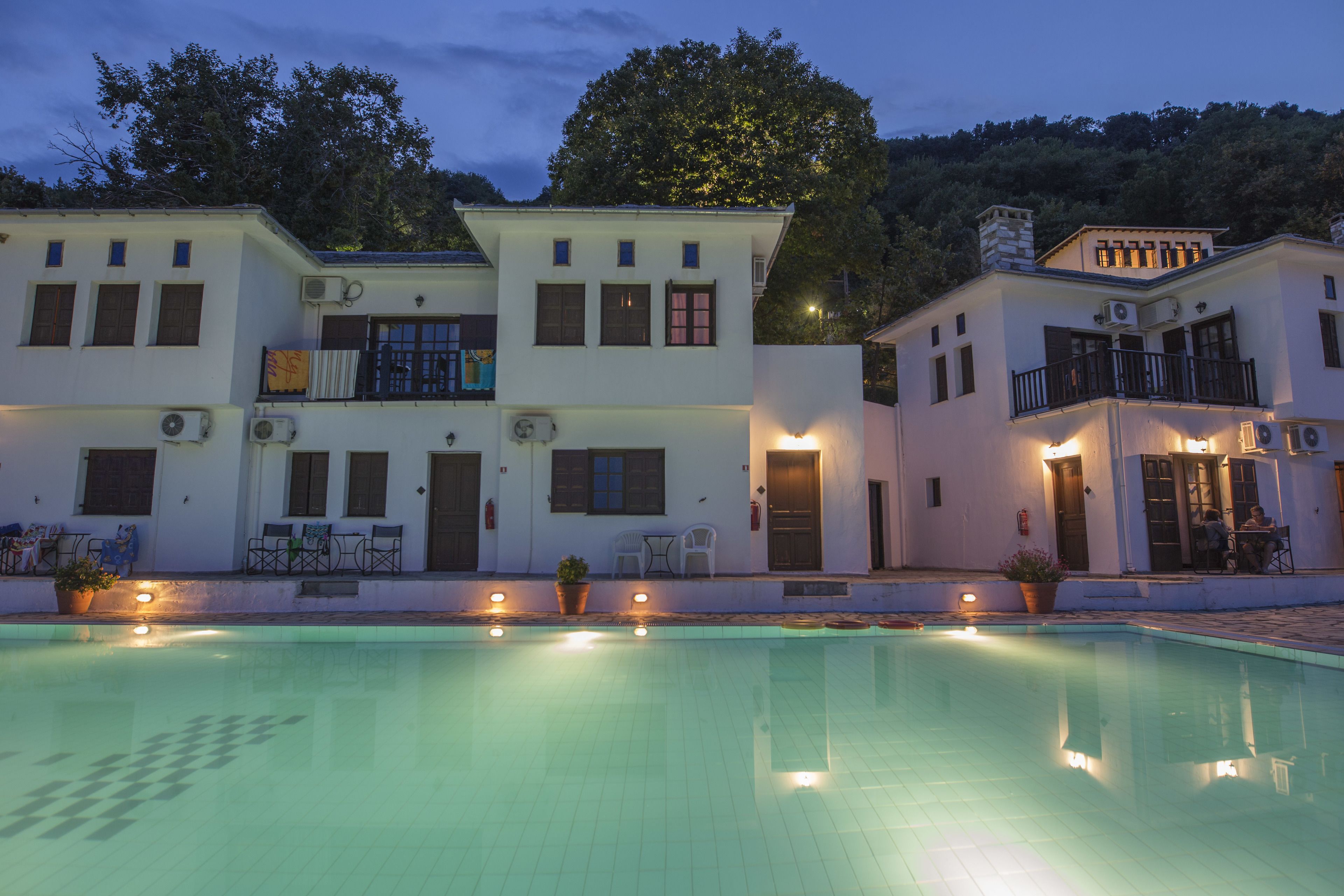 Un hotel de varios pisos con piscina, mobiliario exterior y un balcón.