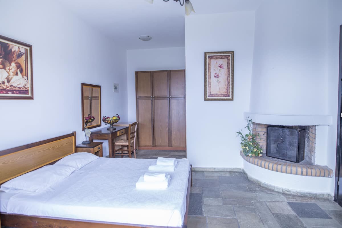 Un dormitorio con cama, escritorio, armario y chimenea.