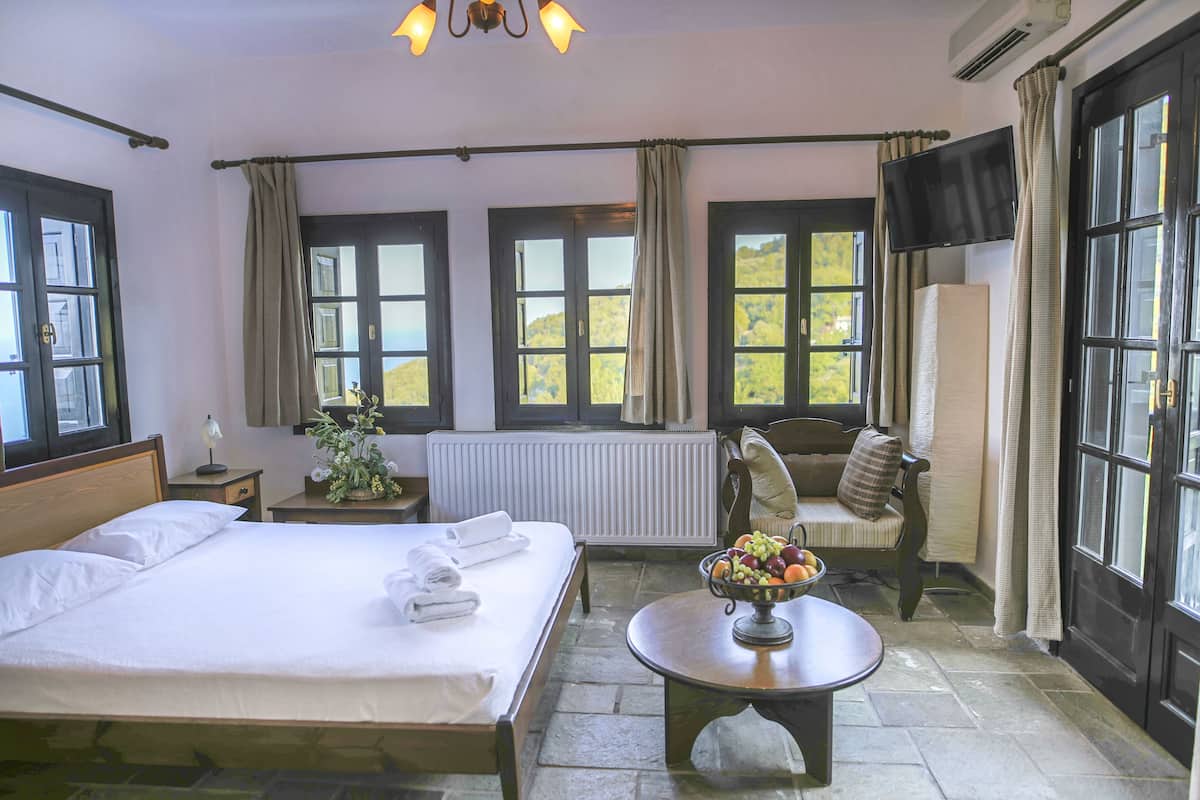 Una habitación de hotel con cama, una mesa con fruta, una silla y un televisor.