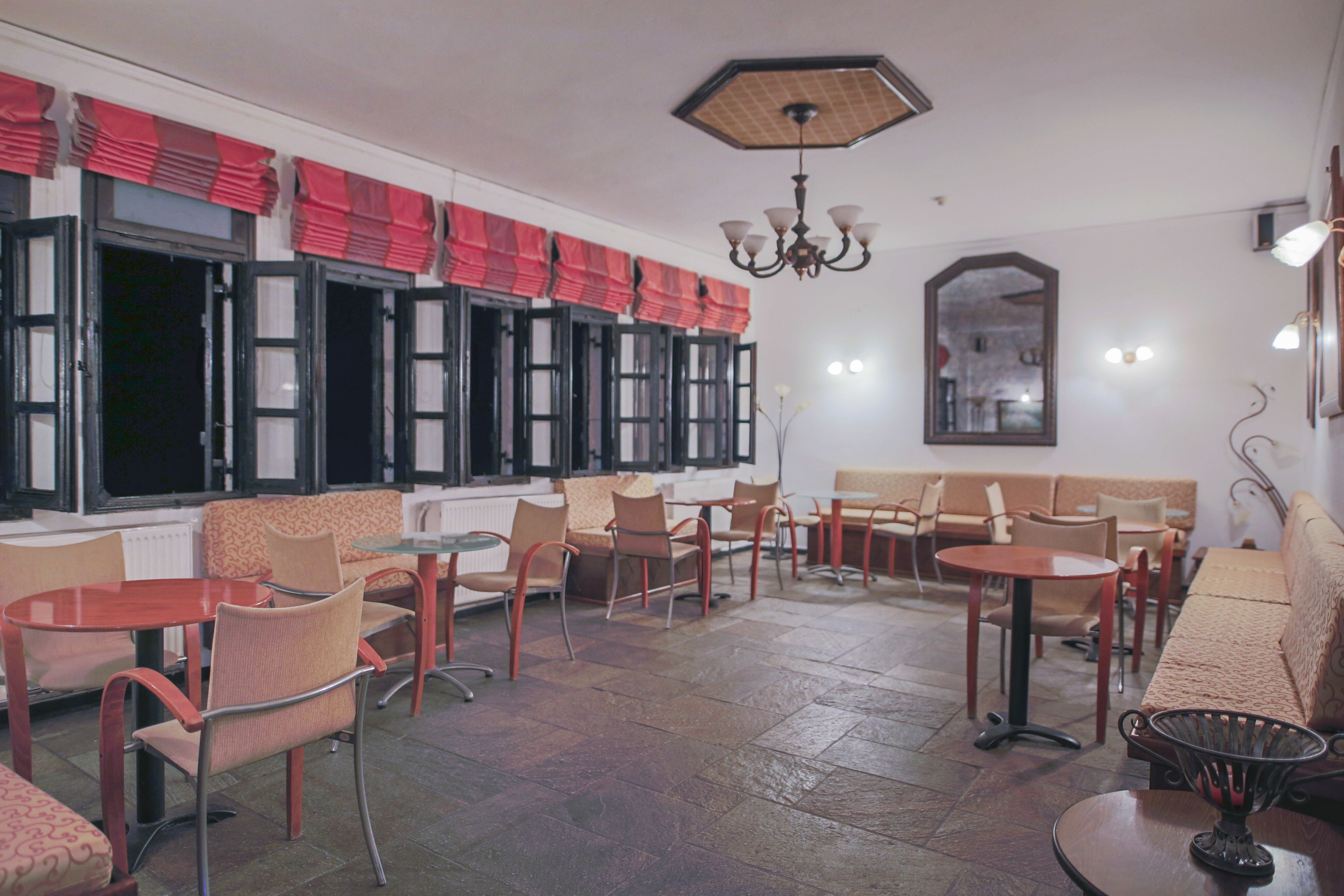 A café with multiple tables and chairs, a sofa, and a chandelier.