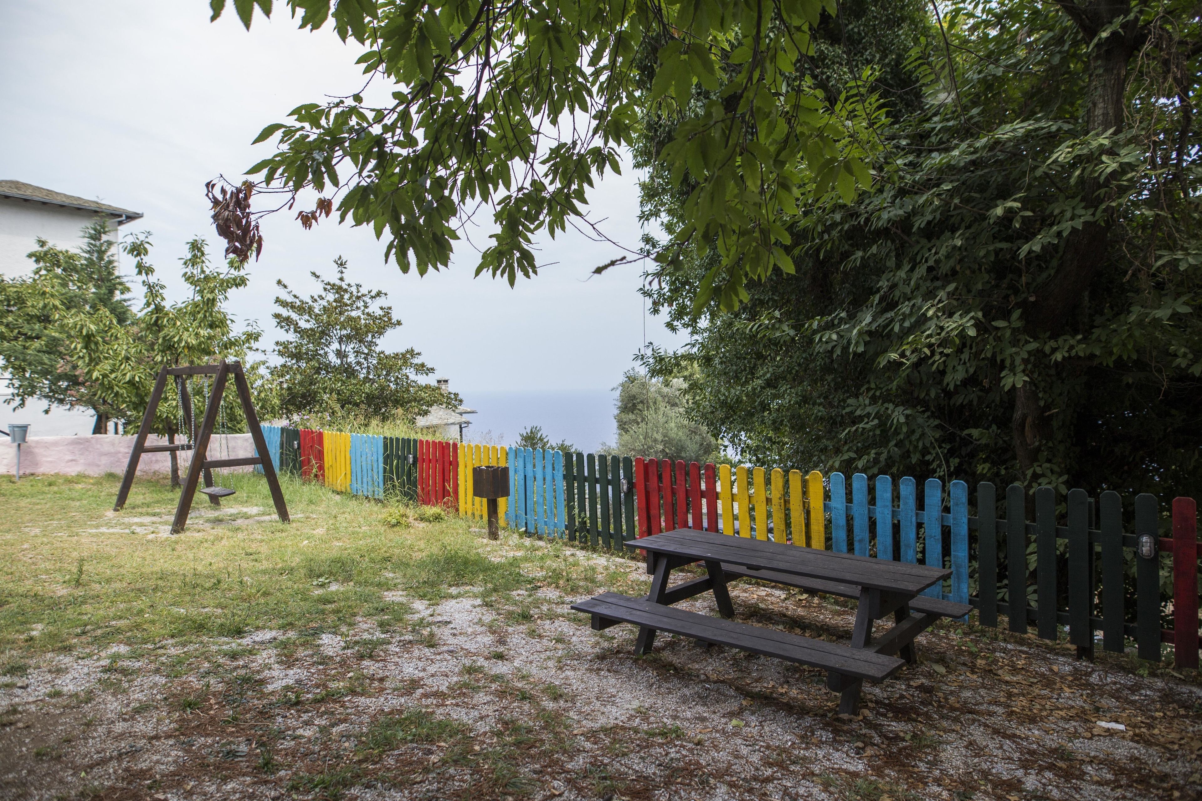 Una mesa de picnic y un columpio en un césped con una valla colorida.