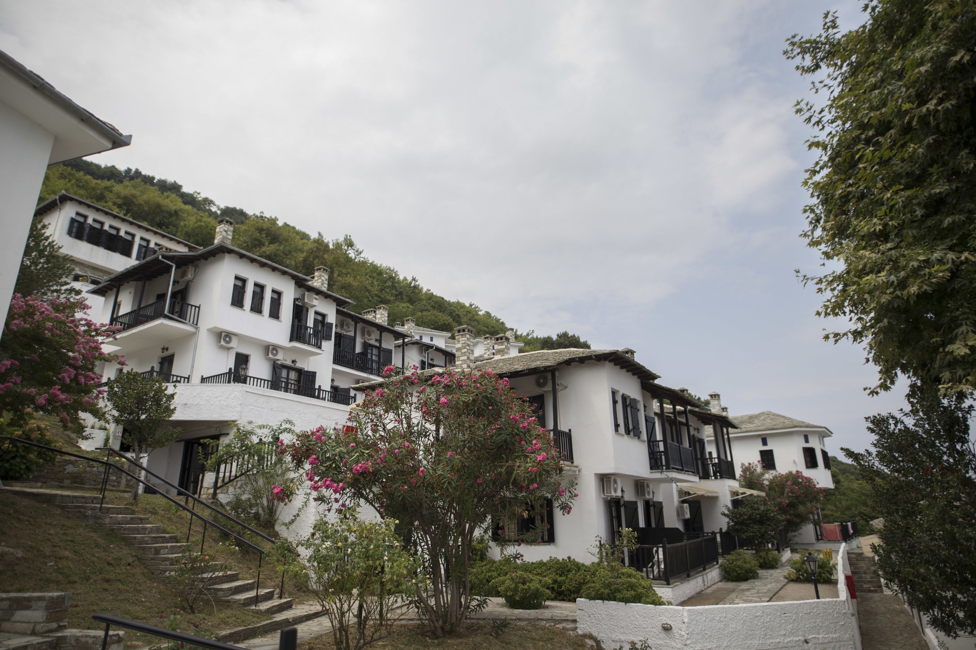 A hillside residential area with white buildings featuring balconies and a staircase leading up.