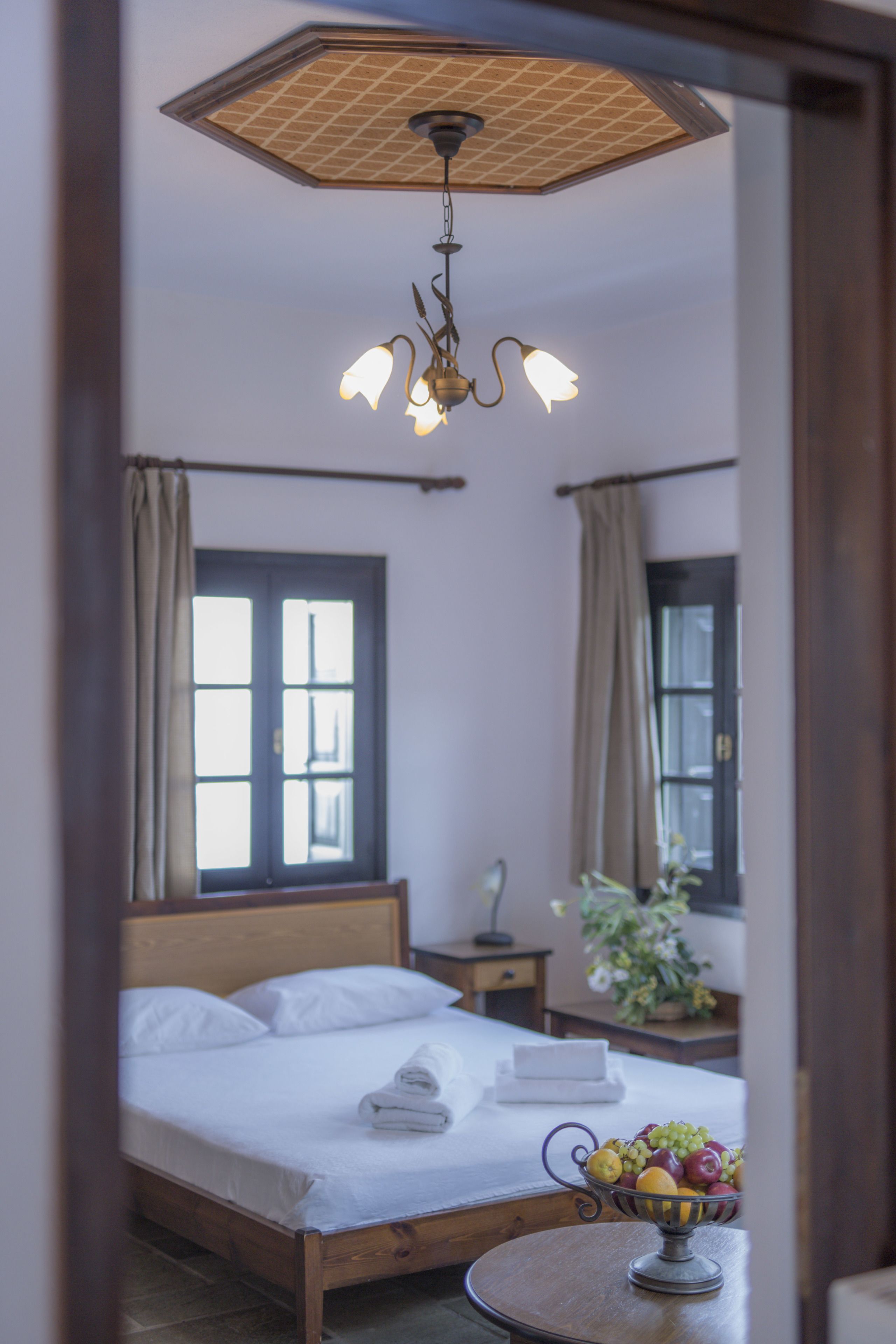 Une chambre à coucher avec un lit, une table de chevet et un panier de fruits posé sur une table ronde.