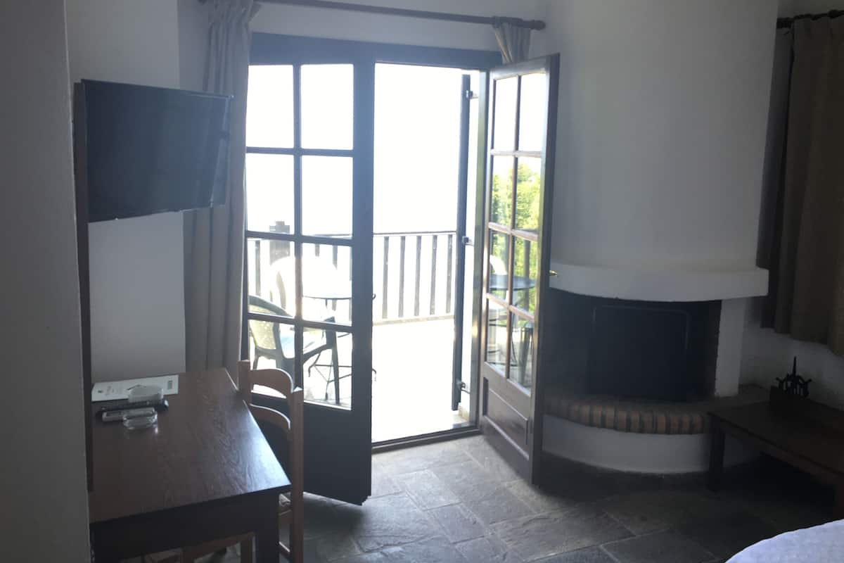 Una habitación con chimenea, una mesa de comedor y vistas a un patio exterior a través de un ventanal.
