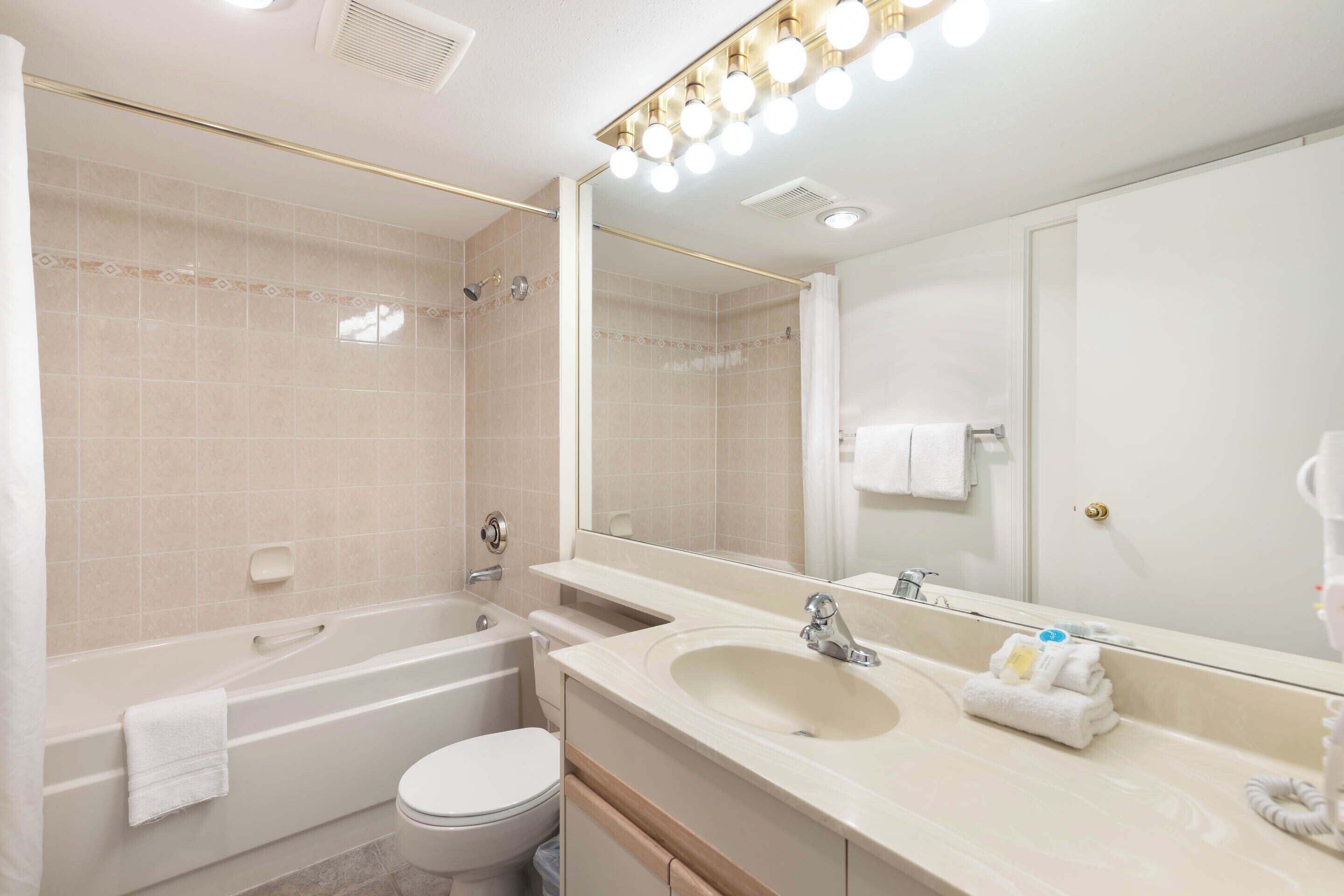 A modern bathroom with a bathtub, toilet, sink, and large mirror.
