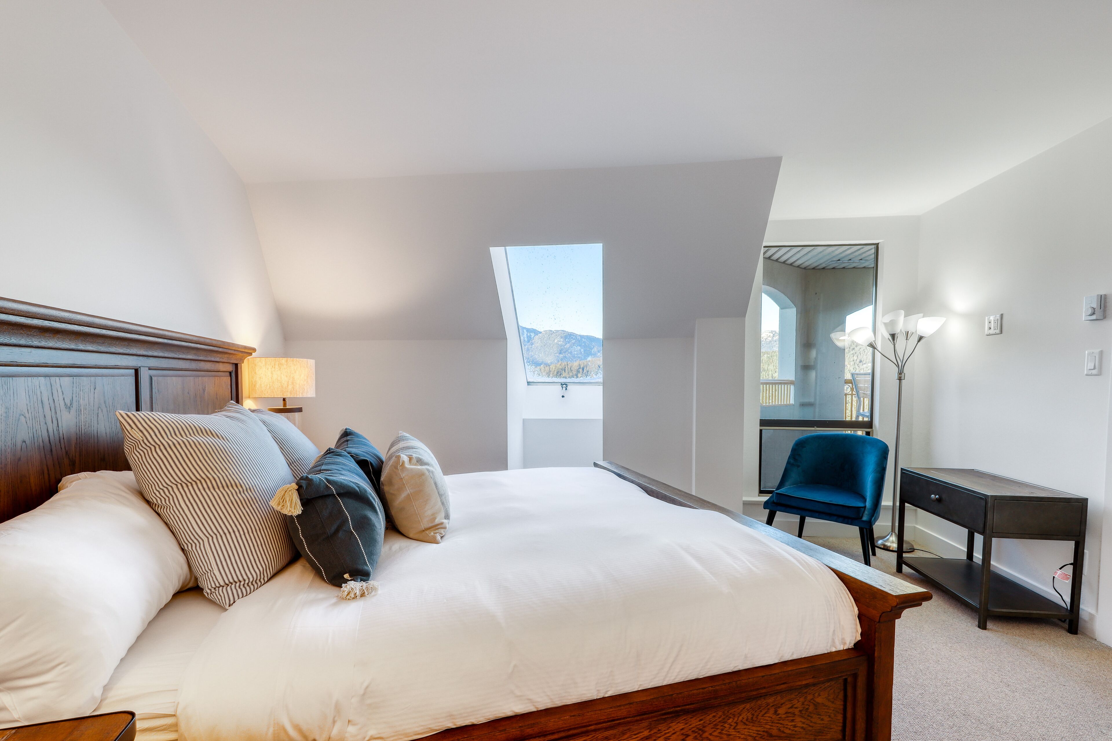 Une chambre avec un grand lit, un bureau et une chaise. Il y a une fenêtre donnant sur les montagnes.