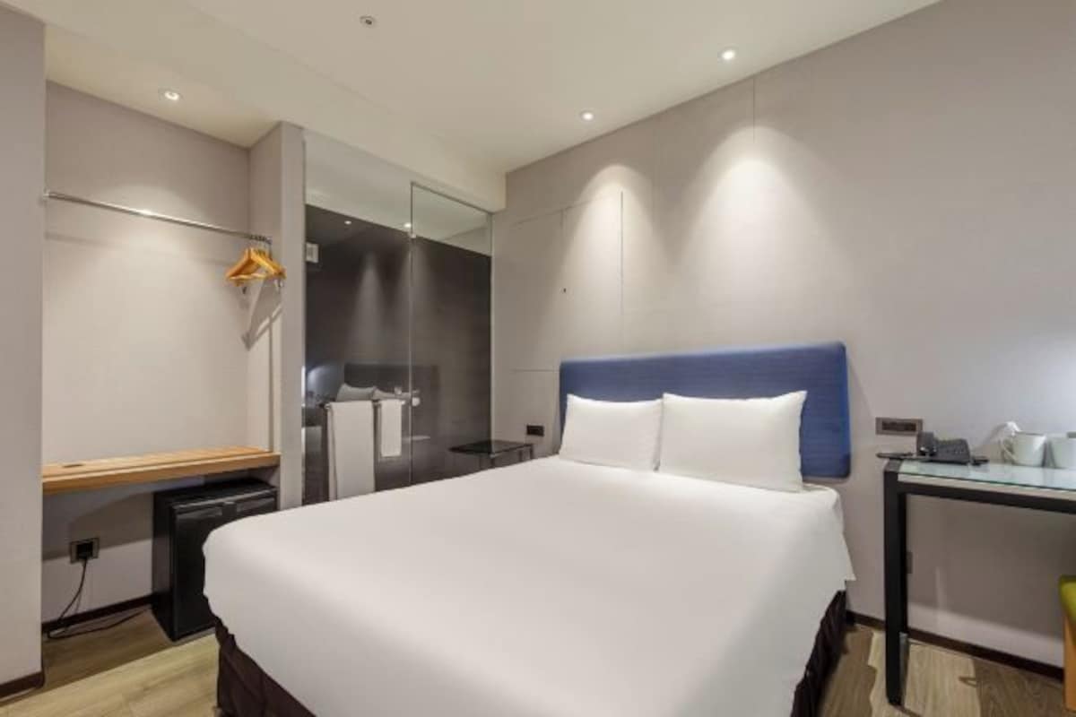 Una habitación de hotel moderna con una cama grande, un escritorio y un espejo.
