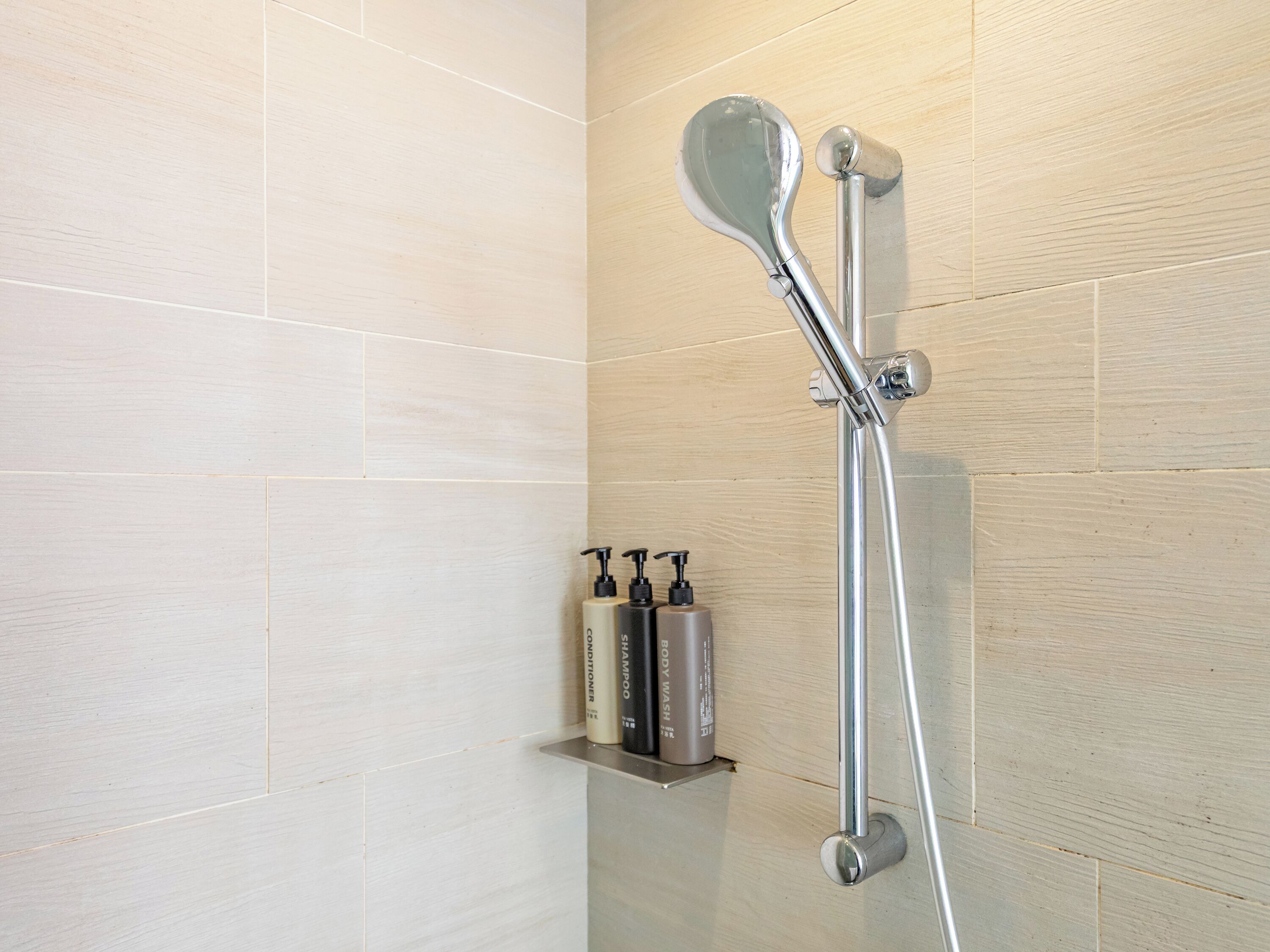 A shower with a handheld showerhead and a wall-mounted faucet.