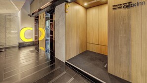Un moderno vestíbulo de hotel con mostrador de recepción, escritorio de información y una pared de madera con un letrero.