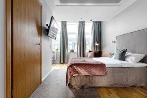 A modern bedroom with a bed, a TV mounted on the wall, and a window with curtains. - Biz Apartment Gärdet (Stockholm)