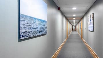 Een hotelhal met een lange gang, grijze muren en een vloerbedekking.
