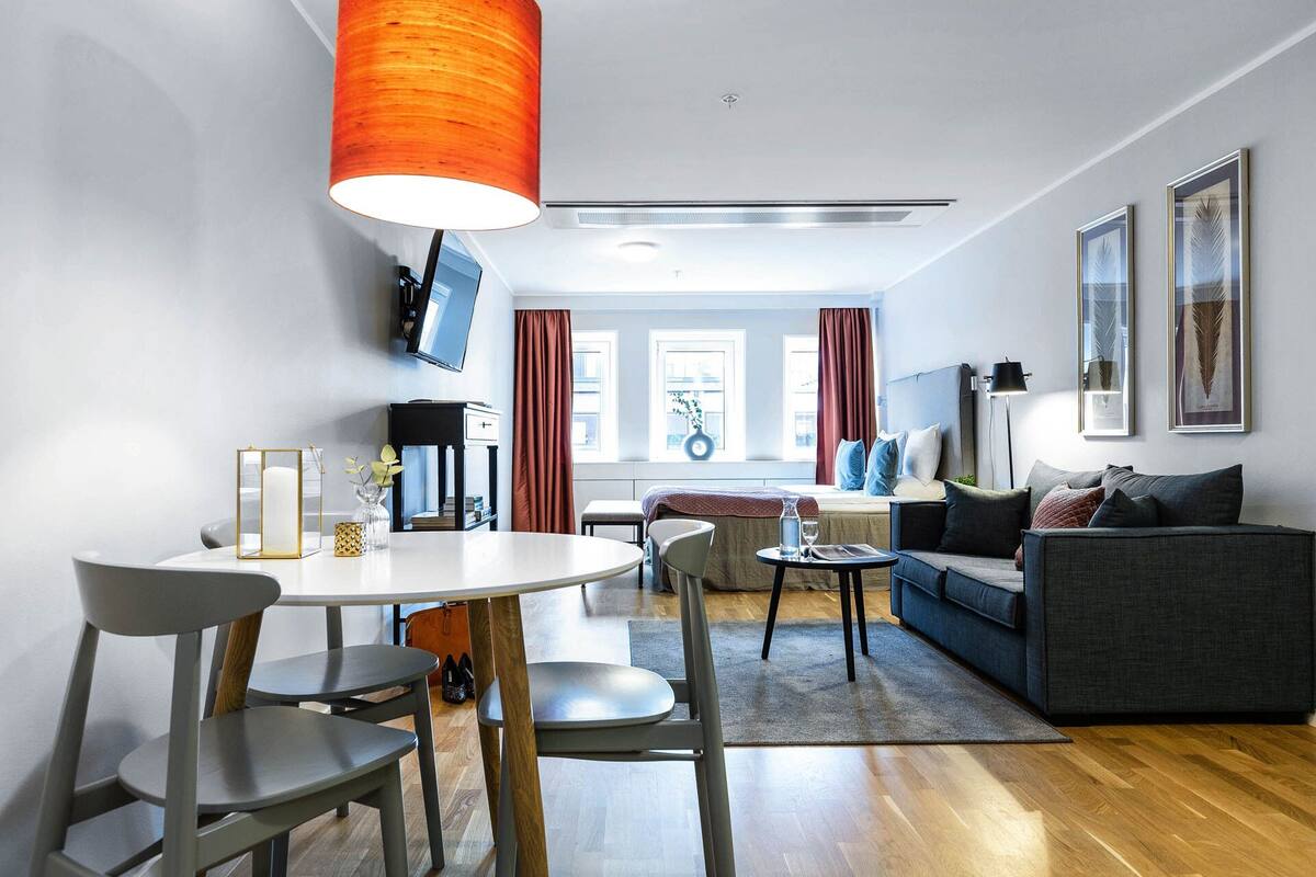 Een moderne woonkamer met een eethoek, een bank, een salontafel en een aan de muur bevestigde televisie.