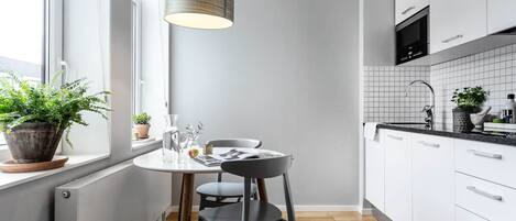 A modern kitchen with white cabinets, a black countertop, and a wooden floor.