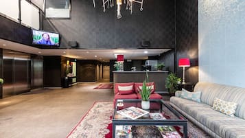 A modern lobby with a sofa, coffee table, and a TV screen.