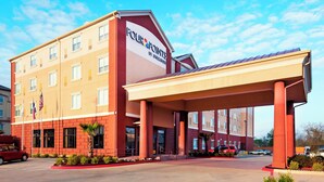 A Four Points by Sheraton hotel with a covered entrance, multiple floors, and a parking lot. - Four Points by Sheraton Houston Hobby Airport (Houston)