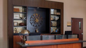 A reception desk with a wooden finish, a decorative wall piece, and a pegboard with various items. - Four Points by Sheraton Houston Hobby Airport (Houston)