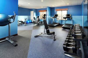 Un gimnasio con cintas de correr, elípticas y pesas libres.