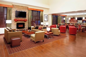 A hotel lobby with a fireplace, seating area, and a bar. - Four Points by Sheraton Houston Hobby Airport (Houston)