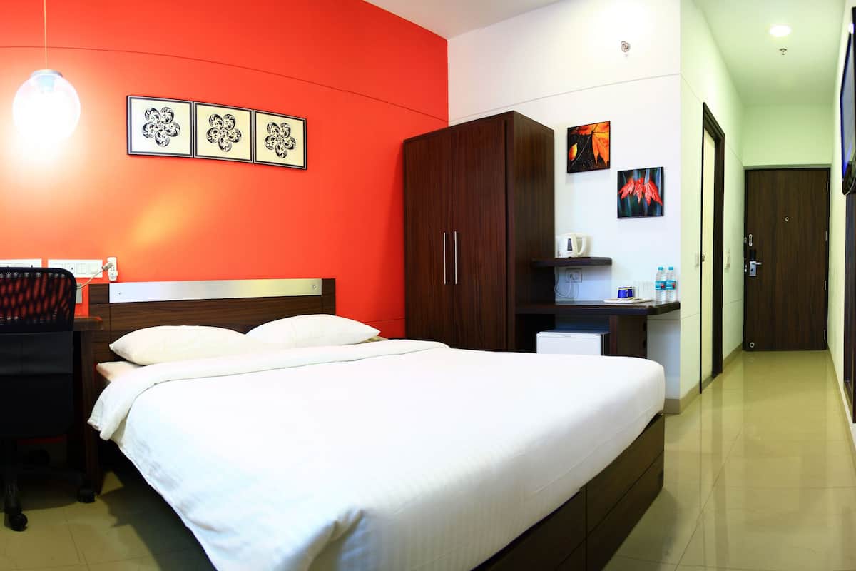 A hotel room with a bed, a desk, a chair, and a TV.