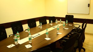 A conference room with a long table, black chairs, water bottles, and a whiteboard. - Ginger Manesar (Gurugram)