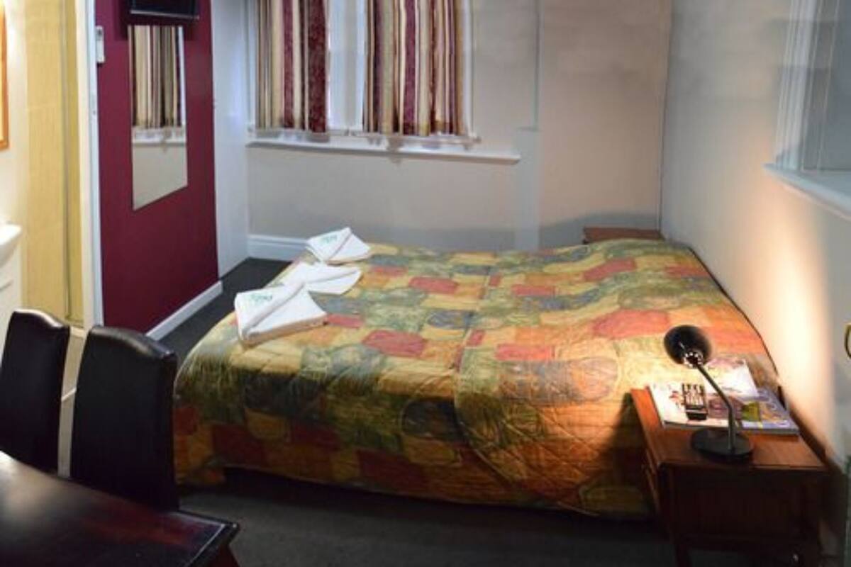 Une petite chambre à coucher, bien rangée, avec un lit, un bureau et une chaise.
