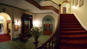 A grand staircase with a red carpet leading up to a wooden door. - Palace Hotel Kalgoorlie (Kalgoorlie)
