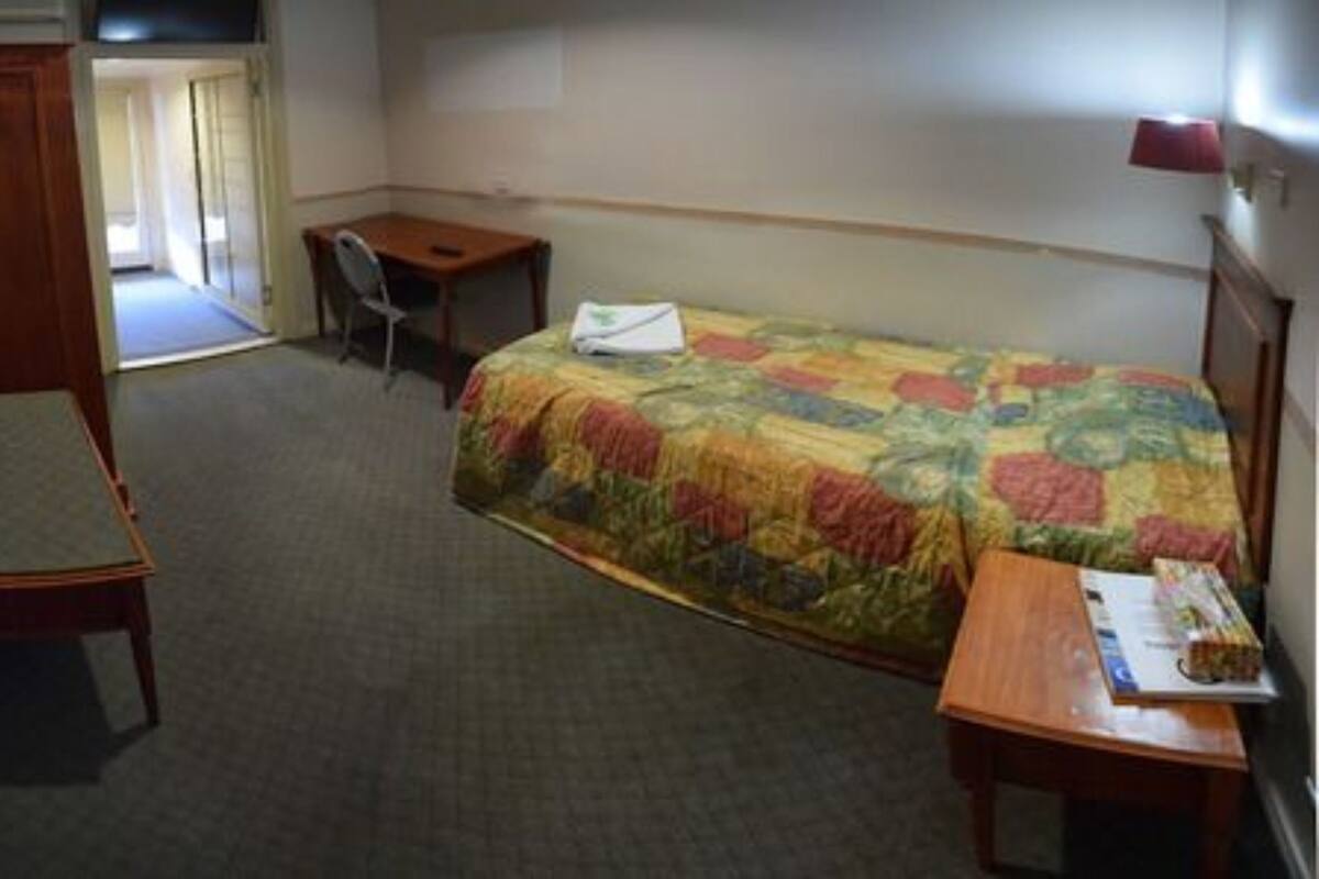 Une chambre d’hôtel avec un lit, un bureau, une chaise et une armoire.