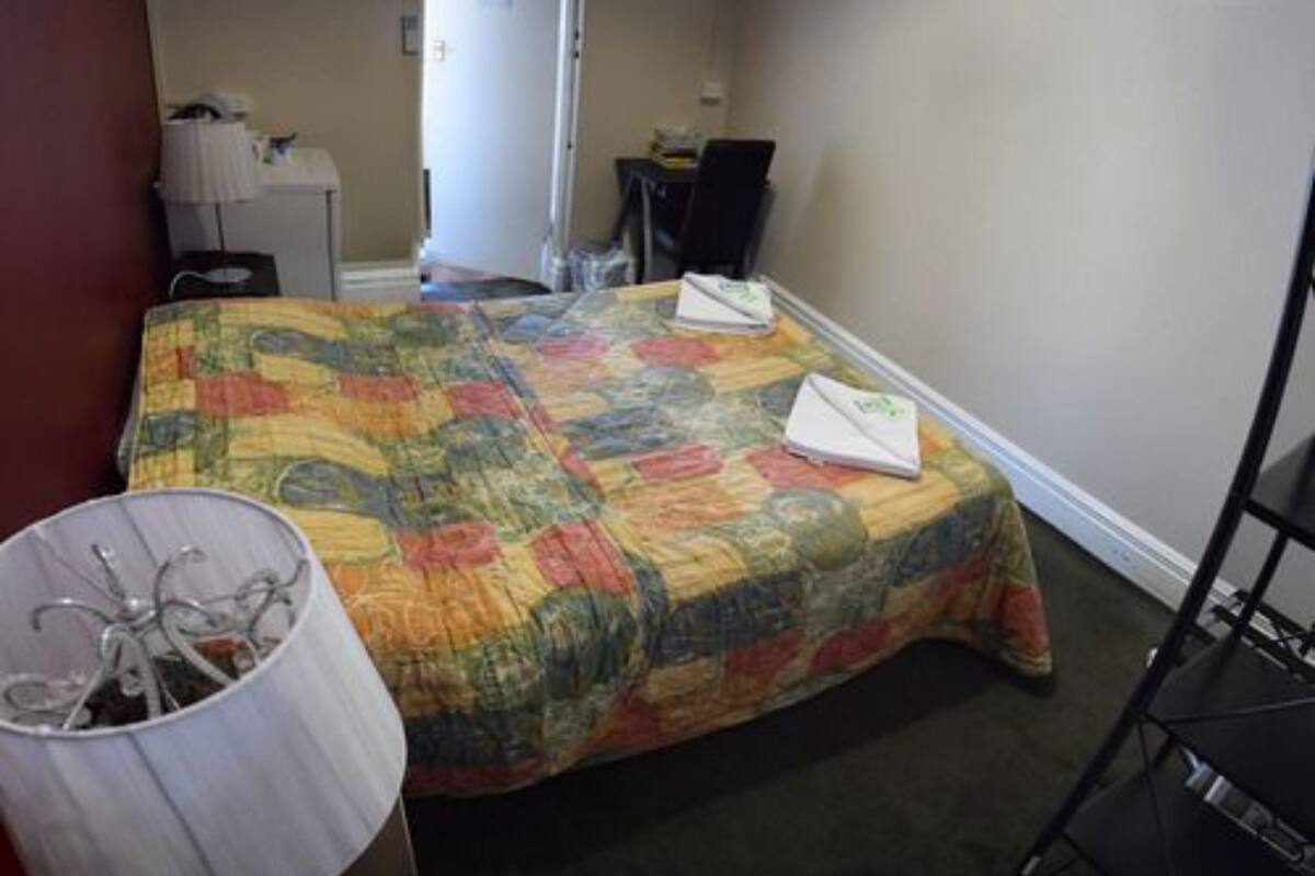 Une chambre à coucher avec un lit, une lampe de chevet, une chaise et un bureau avec un ordinateur.