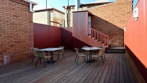 An outdoor patio with wooden flooring and metal tables and chairs. - Palace Hotel Kalgoorlie (Kalgoorlie)