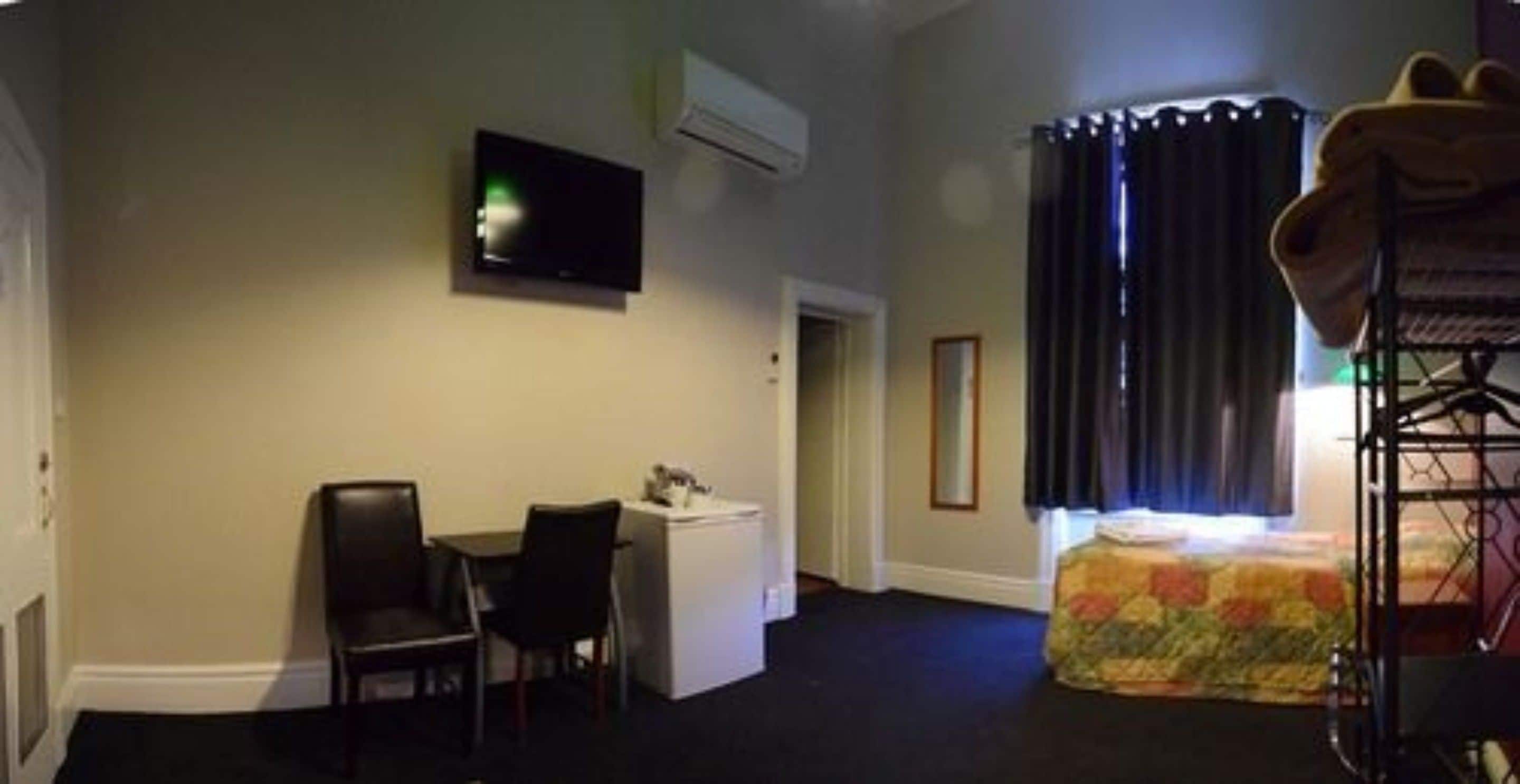 A hotel room with a bed, a desk, a chair, a television, and a window with curtains.