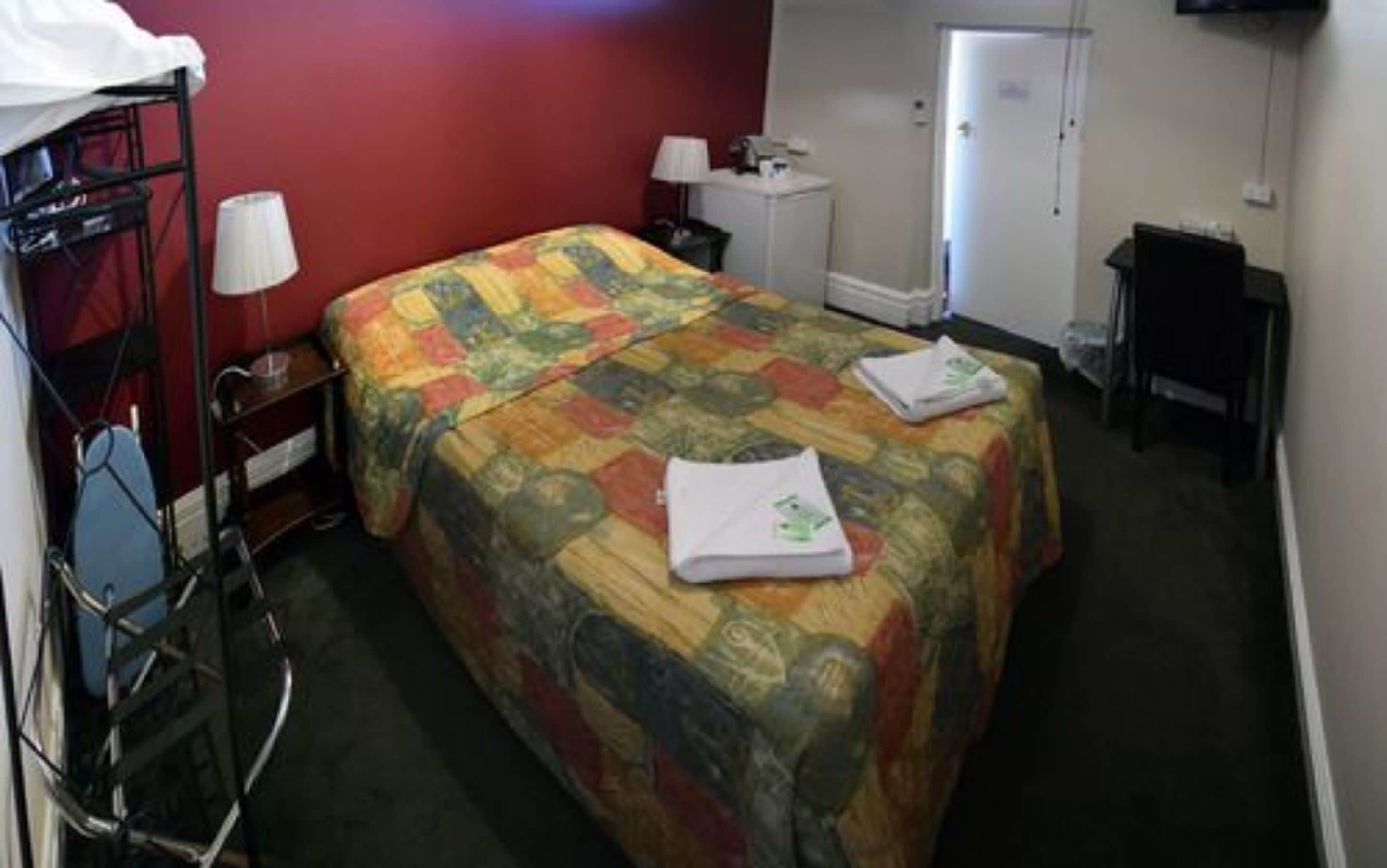 Ein Hotelzimmer mit Bett, Schreibtisch, Stuhl, Lampe und einer Tür.