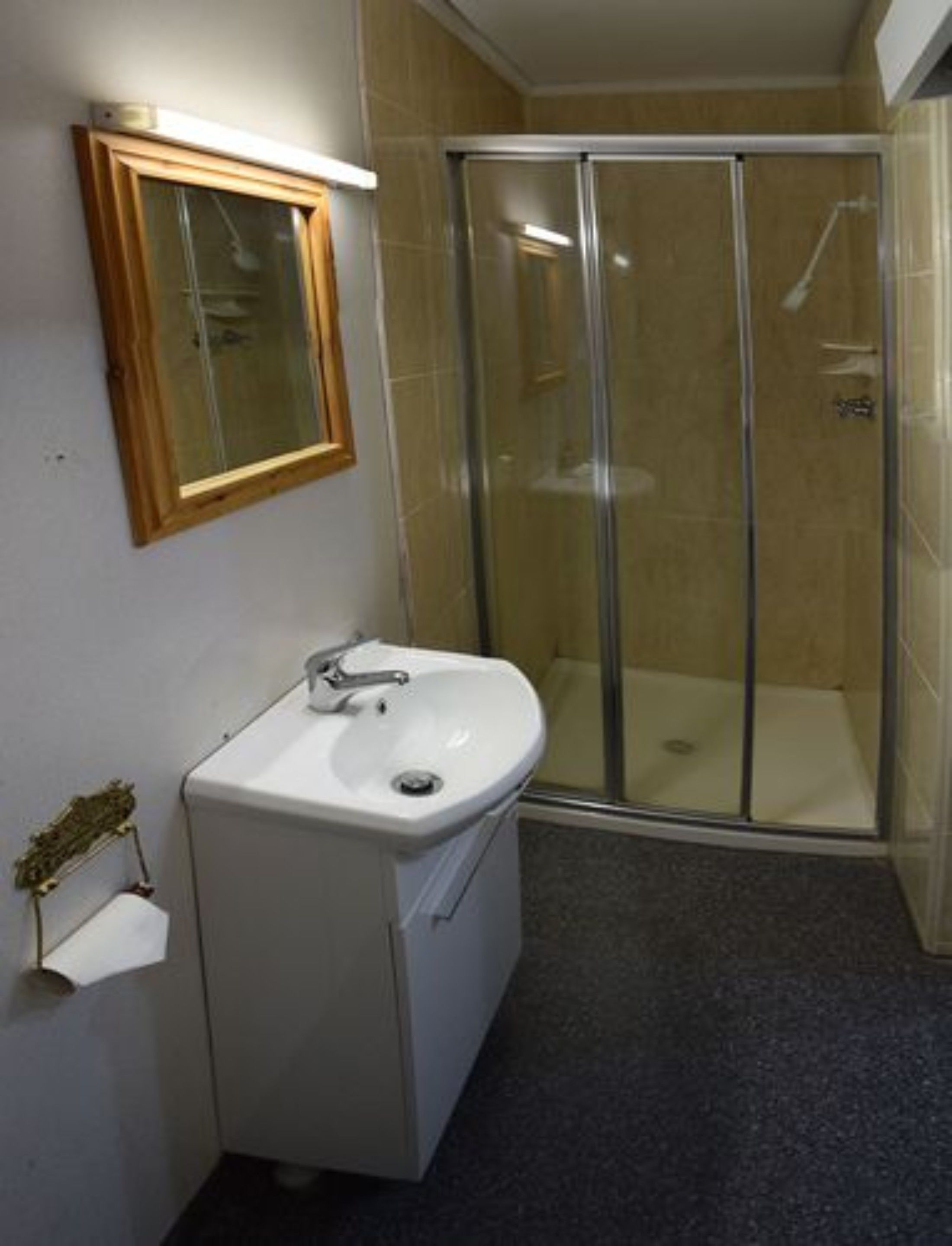Un baño con lavamanos blanco, espejo y cabina de ducha de vidrio.