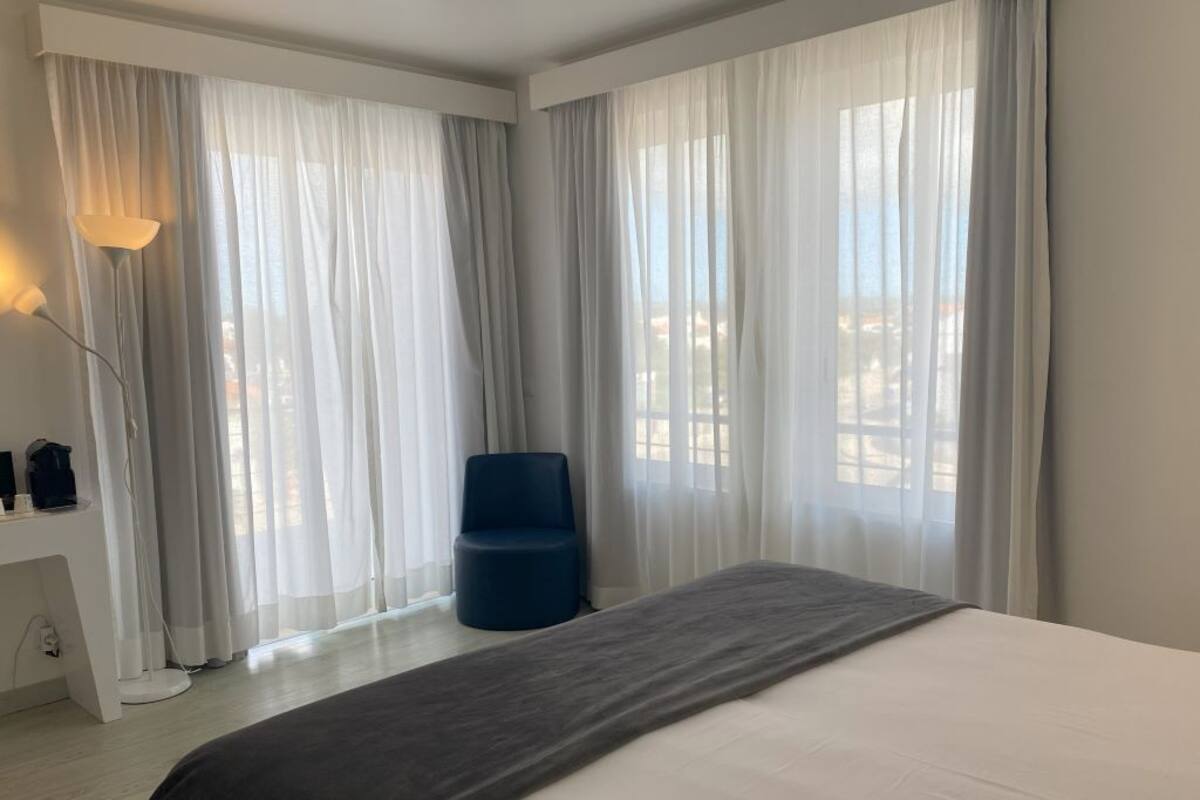 Een hotelkamer met een bed, een bureau met lamp en een stoel.