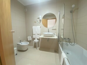Ein Badezimmer mit Badewanne, Waschbecken, Toilette, Spiegel und Handtuchhalter.