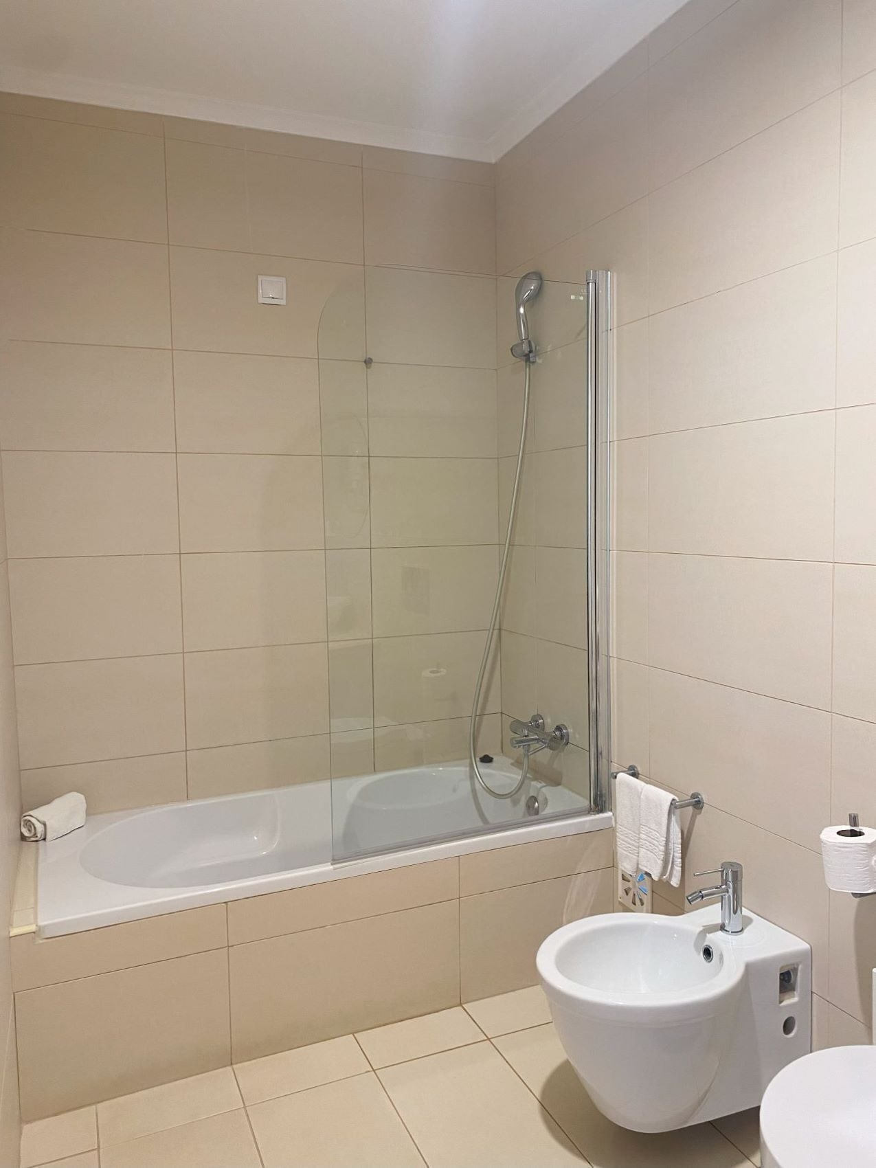 Un baño moderno con ducha envuelta en vidrio, una bañera independiente, un lavabo sobre pedestal y un inodoro.