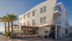 Un hôtel moderne à la façade incurvée, doté de nombreux balcons et offrant une vue sur la plage.