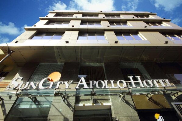 The exterior of the SunCity Apollo Hotel with a modern architectural design, featuring a prominent glass facade and a clear sky in the background. - Hotel Suncity Apollo (Mumbai)