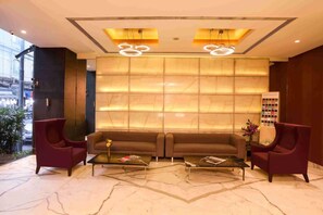A lobby with a sofa, two armchairs, and a coffee table. - Hotel Suncity Apollo (Mumbai)