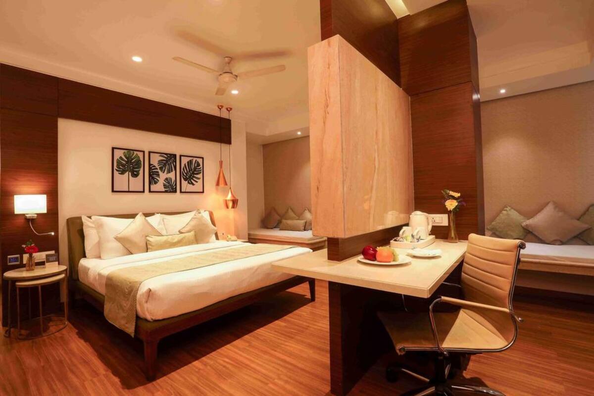 A modern hotel room with a bed, desk, chair, and artwork on the wall.
