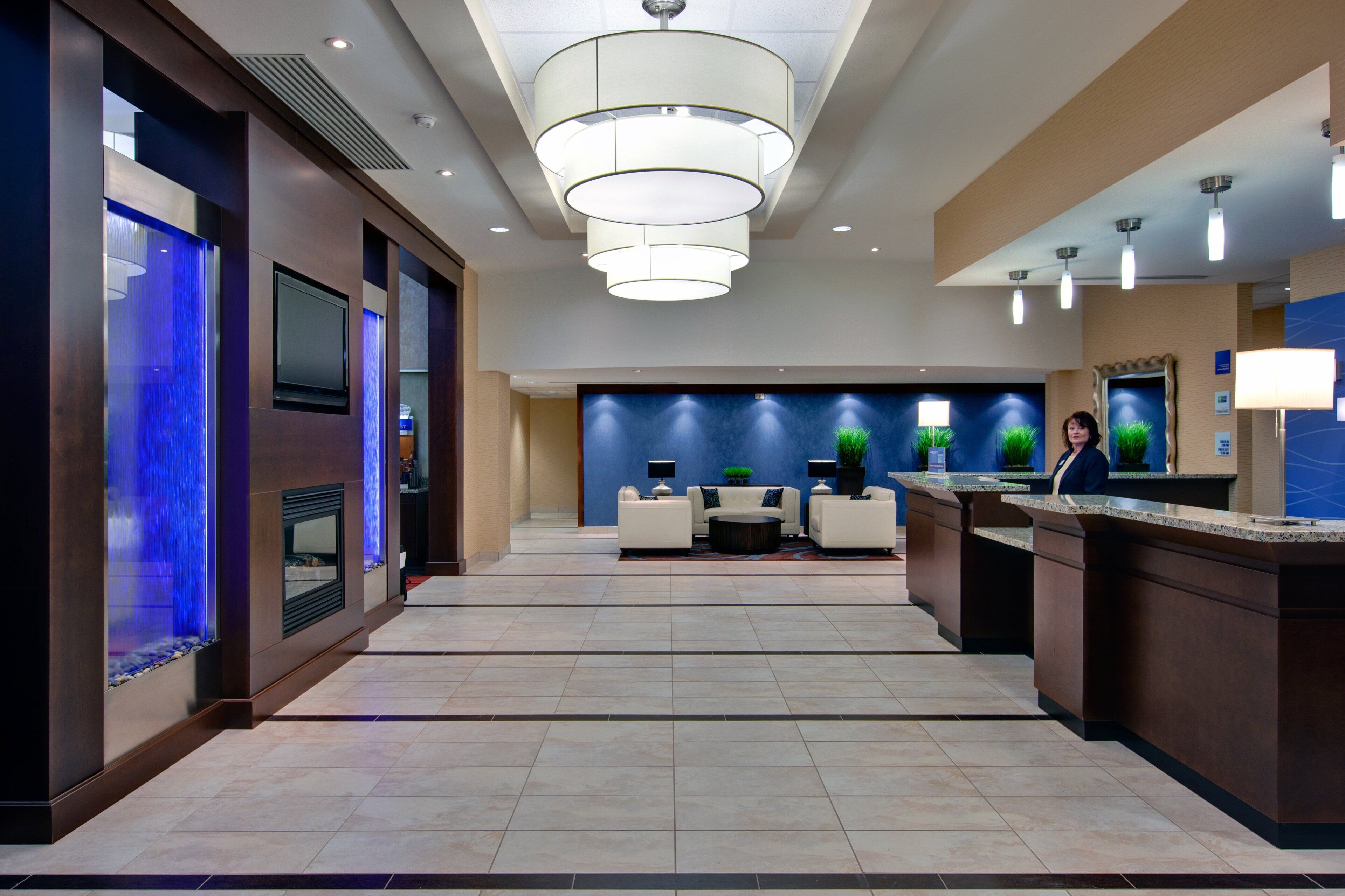 A modern hotel lobby with a reception desk, seating area, and a blue accent wall.