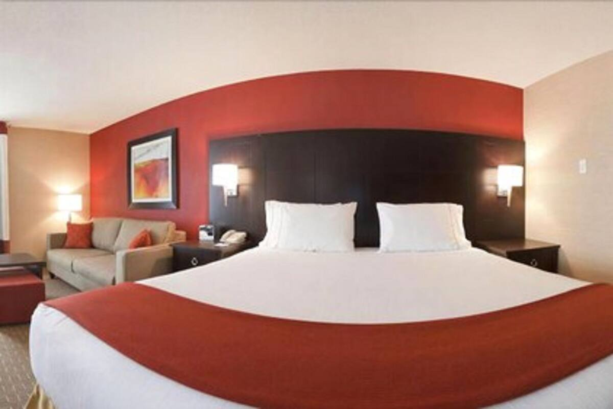 A hotel room with a large bed, a sofa, a desk, and a nightstand.
