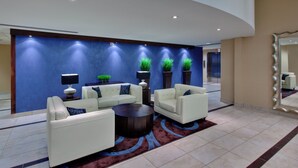 A modern lobby with white sofas, a round coffee table, and decorative plants against a blue wall. - Holiday Inn Express & Suites Chatham South by IHG (Chatham-Kent)